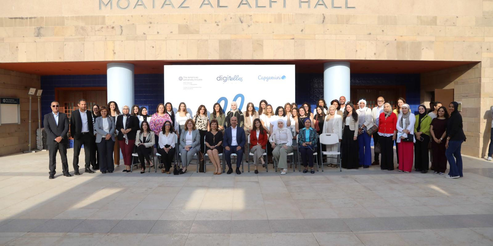 A group of people standing in front of Moataz Al Alfi Hall in a group photo