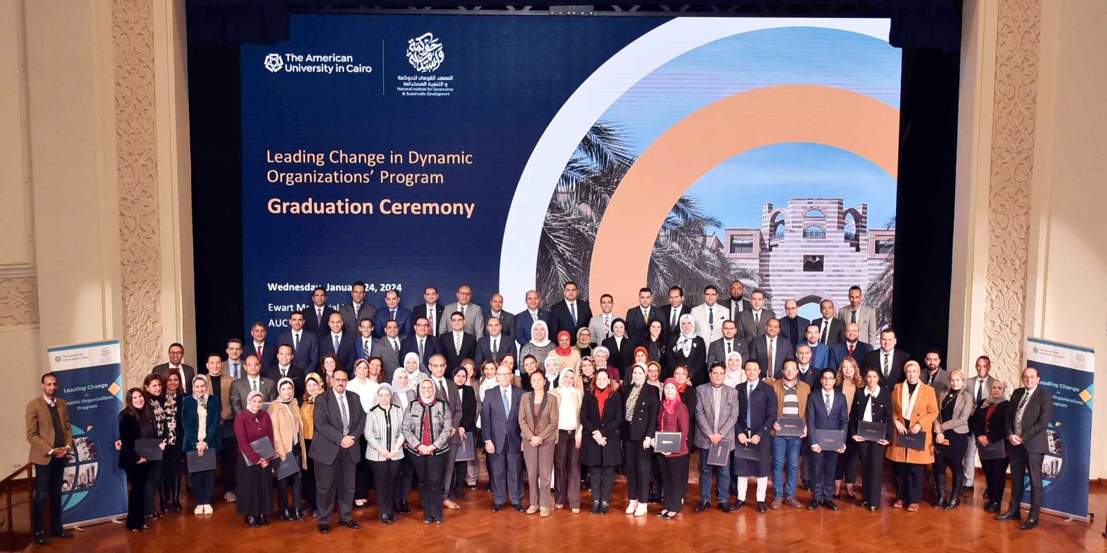 Graduating participants are standing at the stage of Bassily Auditorium 