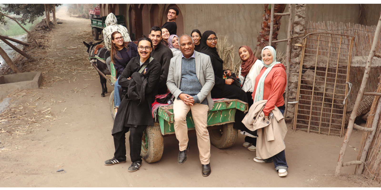 A class sits on the back of a horse drawn cart