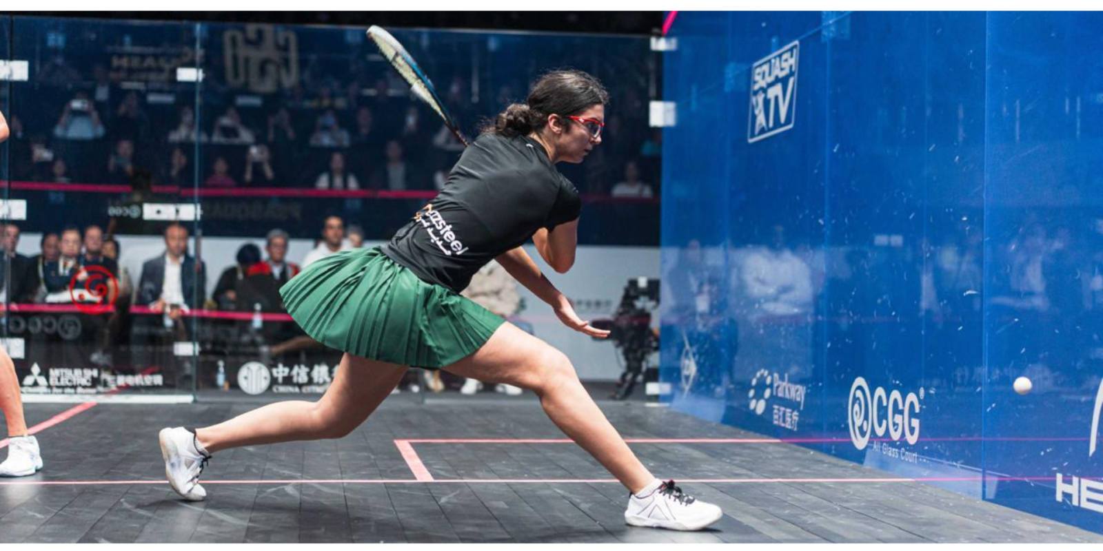 Amina Orfi attacks a squash ball with her racket