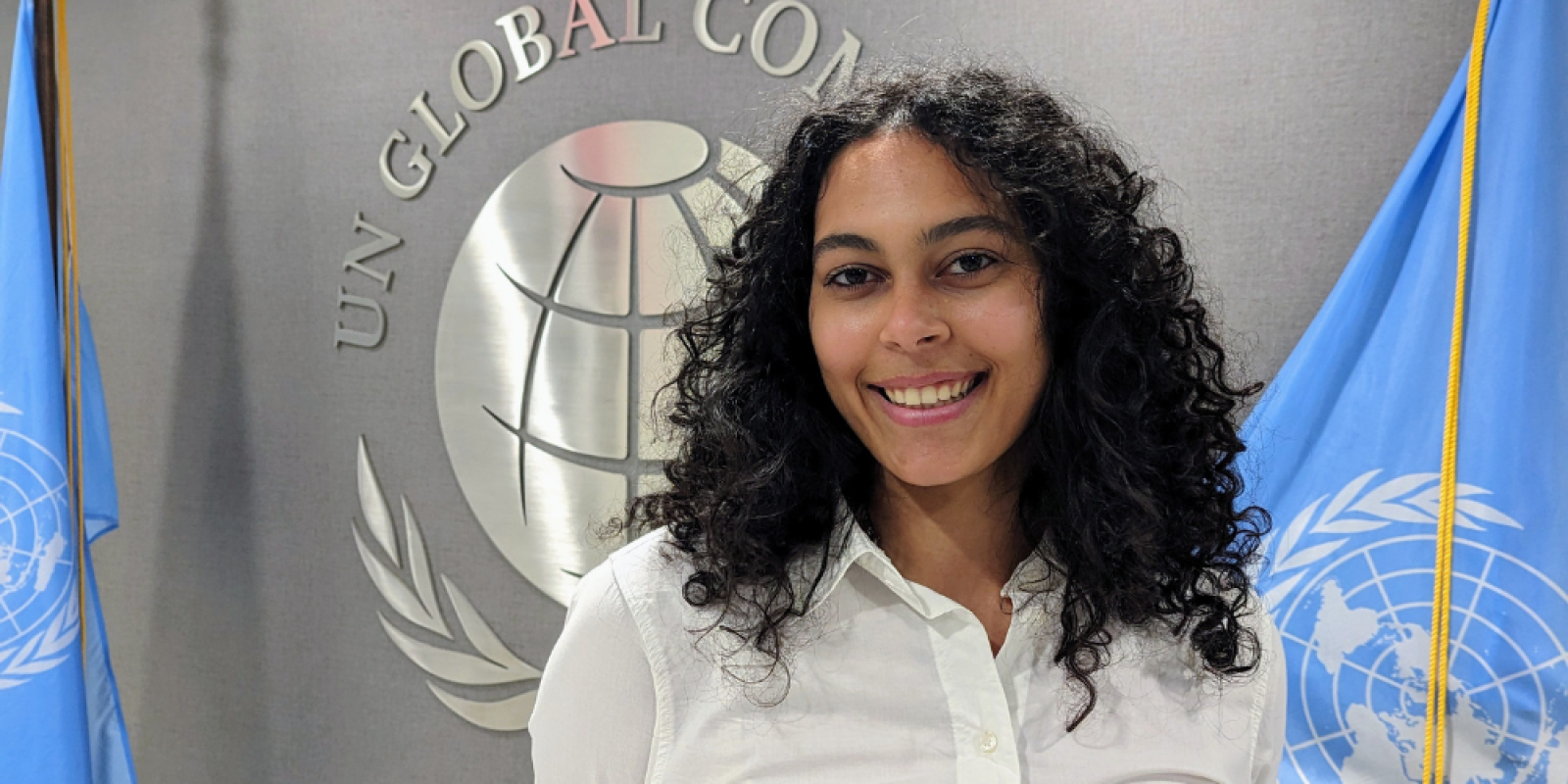 Zein Ibrahim stands next to the flag of the United Nations