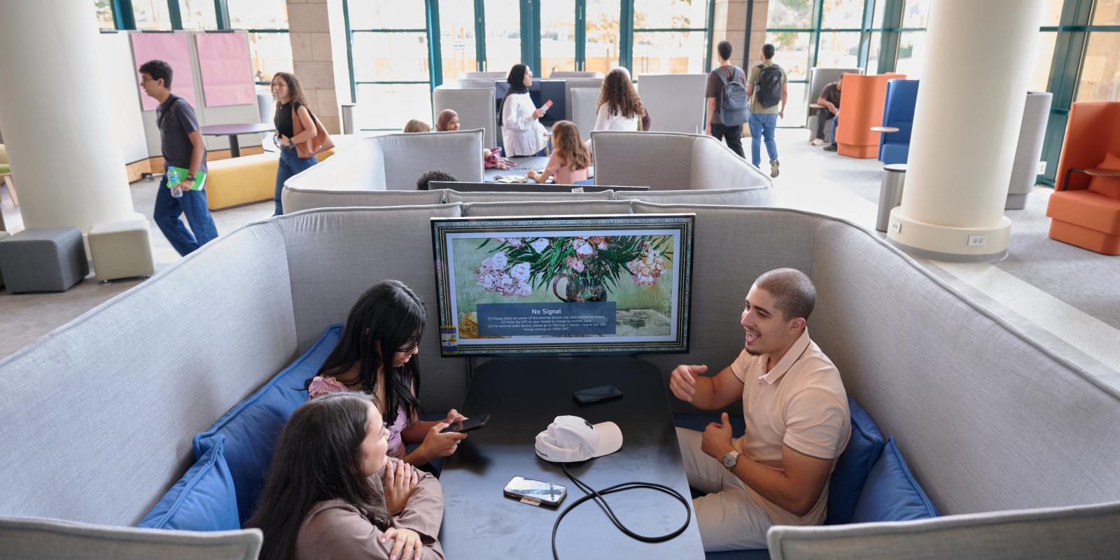 Three students sitting in a booth in the newly renovated library.