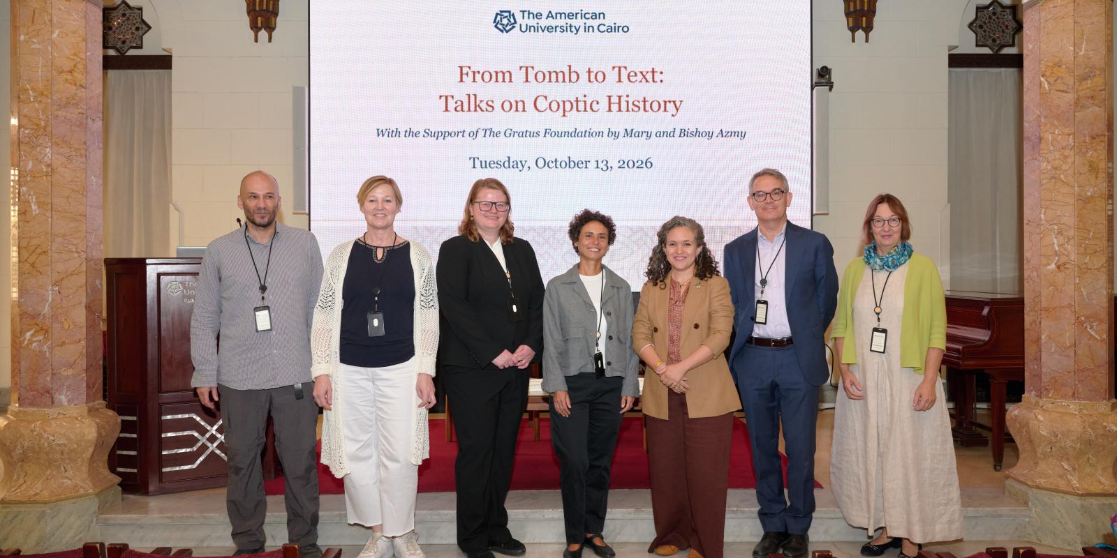 A group of people smiling and standing in front of a banner with the title of the conference