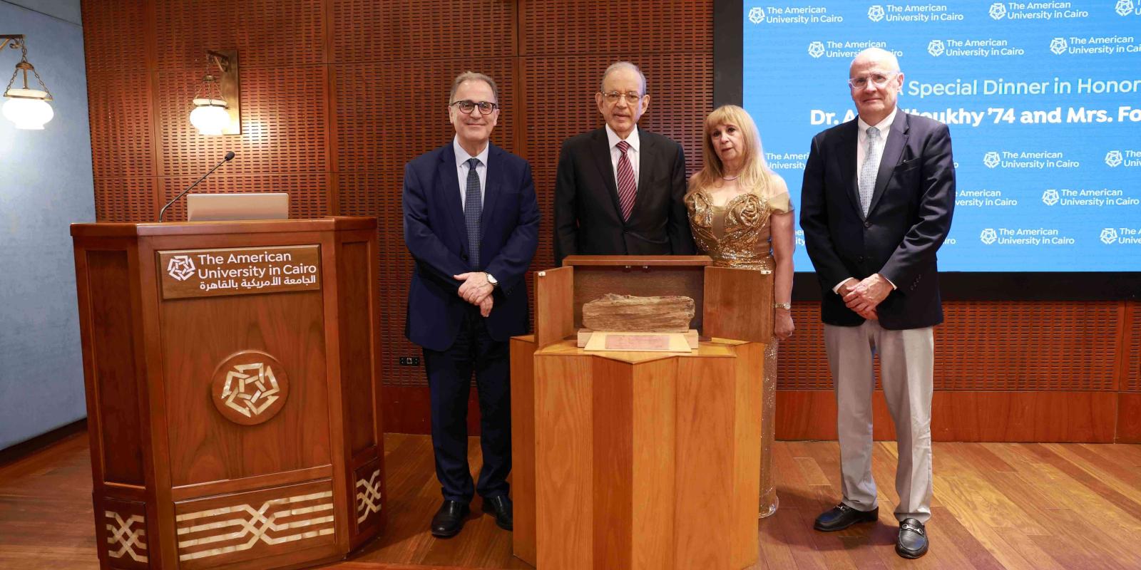 Atef and Fofa Eltoukhy, Chairman of the Board Mark Turnage and AUC President Ahmad Dallal standing in front of a screen