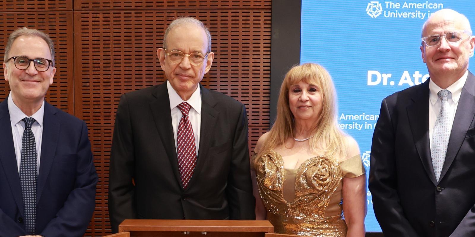 Atef Eltoukhy and his wife Fofa stand next to an AUC podium, along with AUC President Ahmad Dallal and Board of Trustees Chairman Mark Turnage