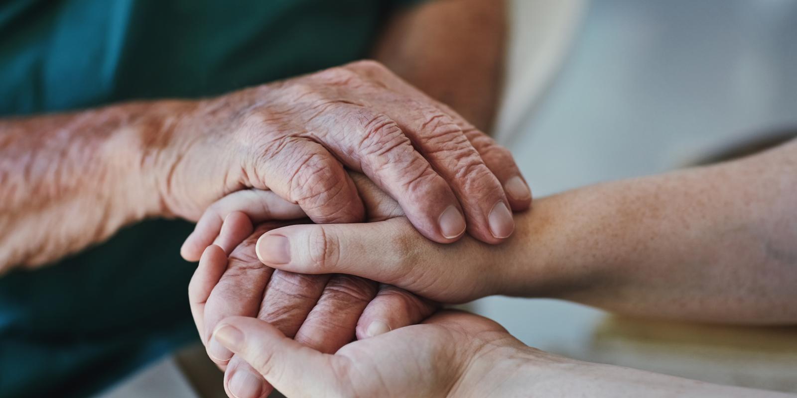 A pair of old hands comfort a pair of young hands.