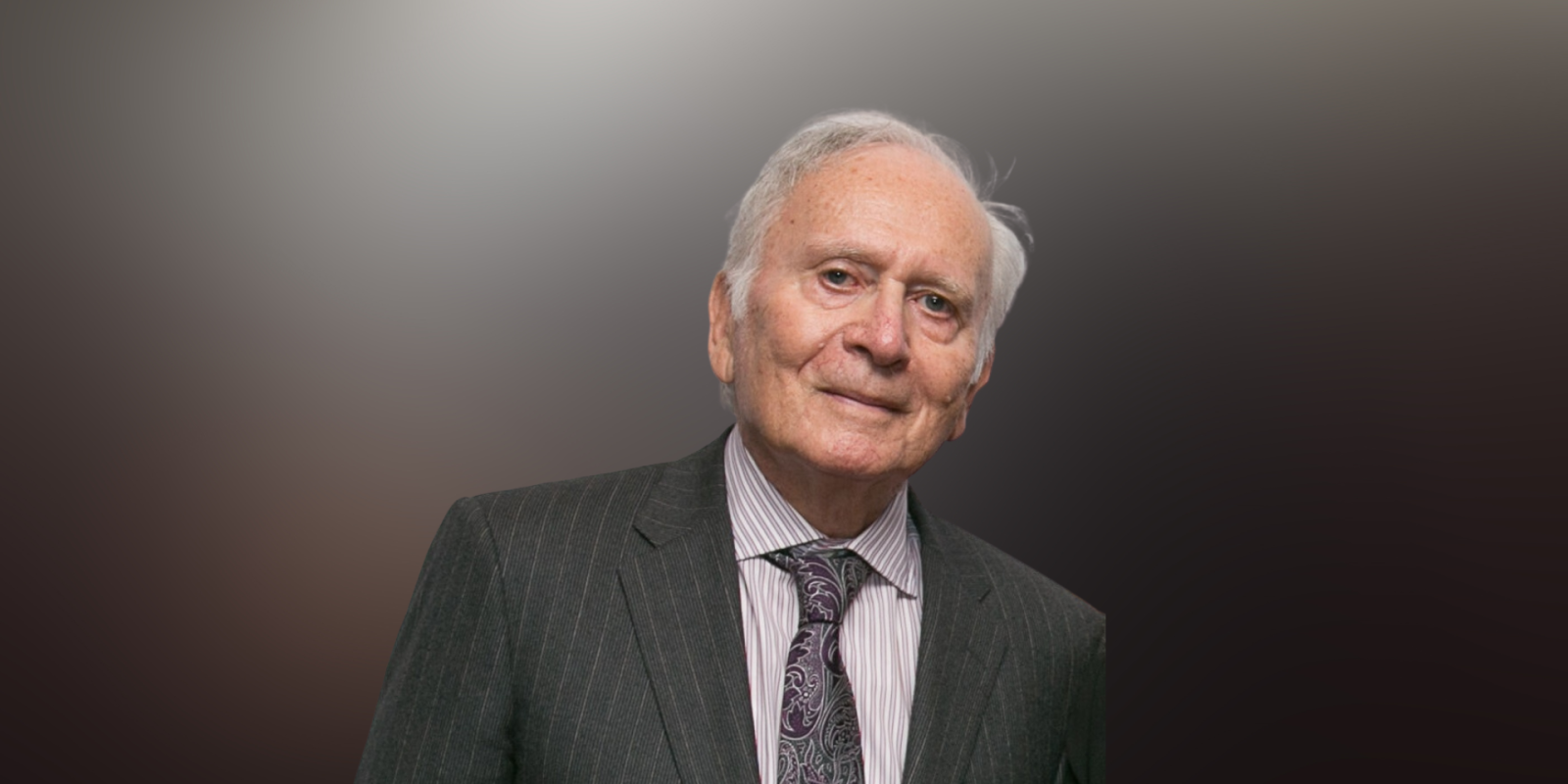 Arthur Lindenauer in a suit in front of a mixed light background