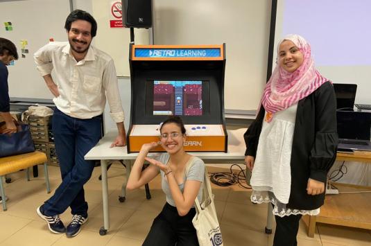Tomorrow's Leaders students pose in front of their project, a game for children to learn about nutrition
