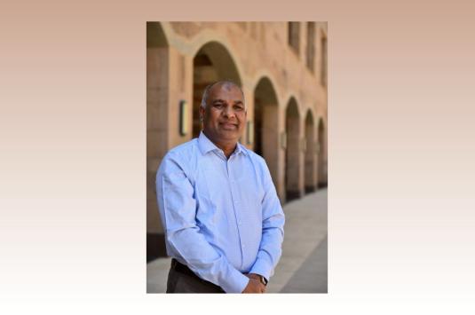 Shahjahan Bhuiyan stands and smiles at the camera in a photo on campus.