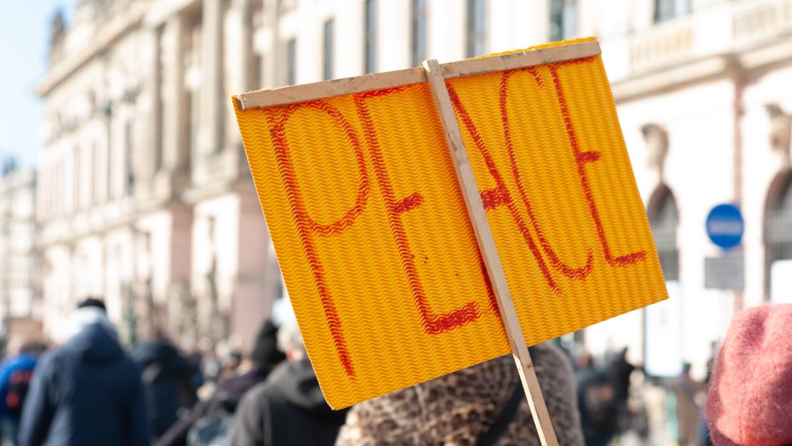 Peace written on a sign held up in a crowd