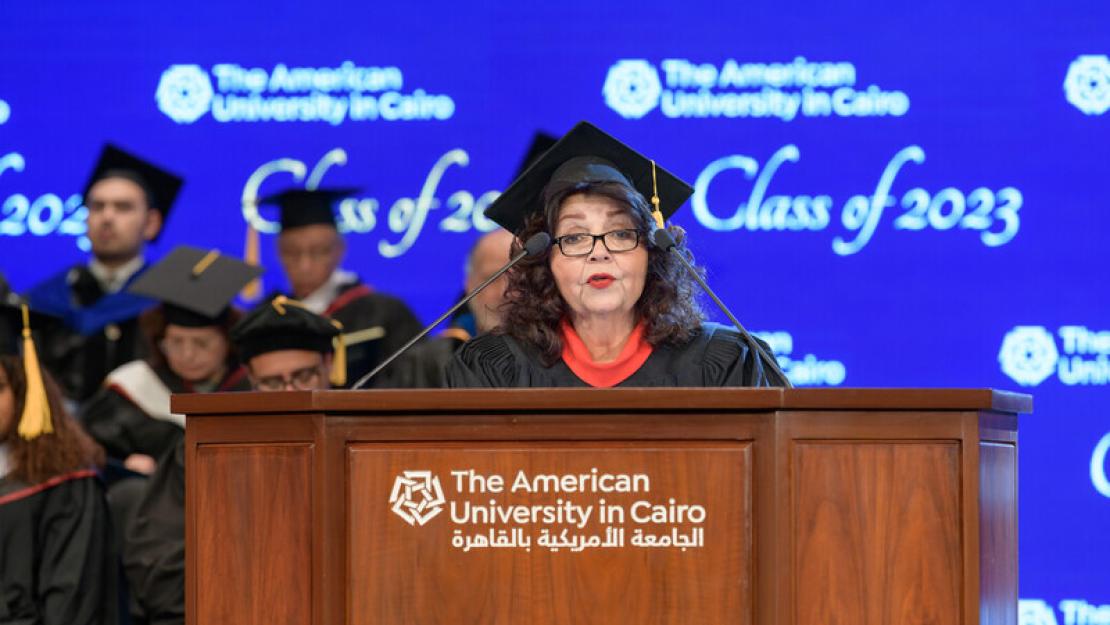 Abdel-Motaal speaks at a podium during commencement while wearing a cap and gown