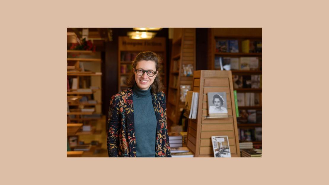 Photo of Veerle De Laet standing and smiling next to book shelves