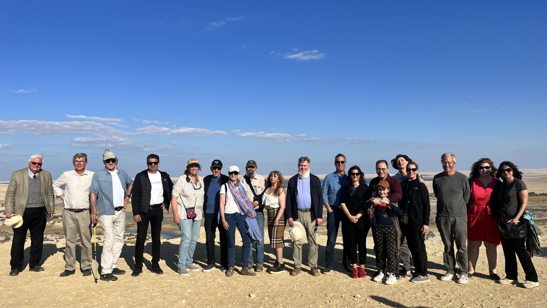 Board members, faculty and staff pose in a line in the desert in Faiyum