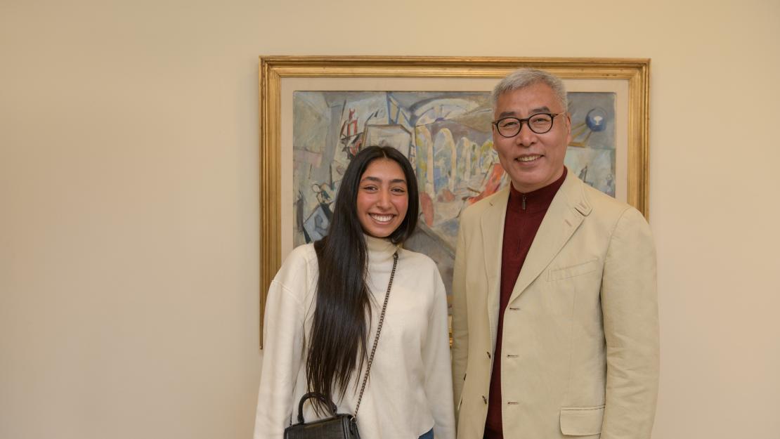 Shahd El Helbawy stands with Wei Liu, smiling in front of a painting.
