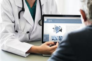 Doctor talking to a man and explaining case on a laptop