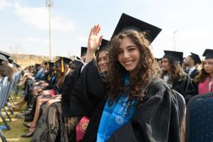 Students in cap in gown sit at commencement