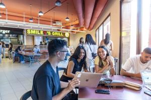 Group of students in food court with a boy holding his laptop