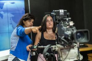 Two women standing behind a camera in preparation to start filming