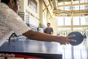 Two male students holding rackets in their hands and playing table tennis in Artoc Sports Court.
