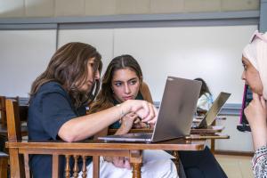 female students working together on project in class and explaining the information to their professor