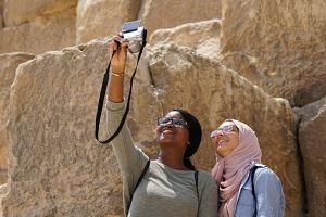 Two girls by the pyramids taking a selfie using a camera