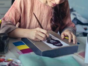 a girl drawing and coloring on a wooden box