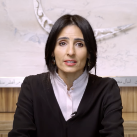 woman with short brown hair wearing brown sweater sits at a desk