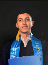 A male wearing his cap and gown and smiling