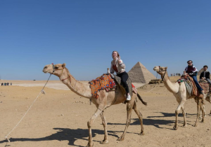 International students riding camels beside the Pyramids