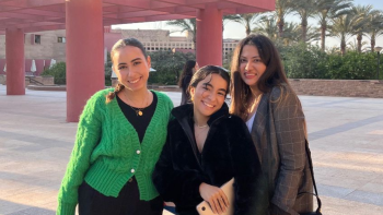 Three women smile on campus