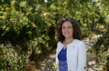 Woman in a blue dress stands in a lush garden