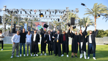 Students stand together throwing their graduation caps