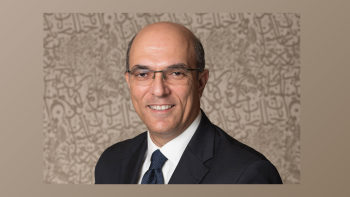 A man in a dark suit and black glasses