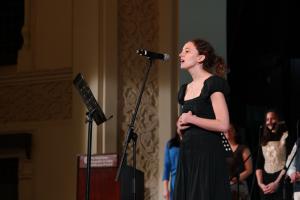 student singing in front of microphone in a concert at AUC ewart hall