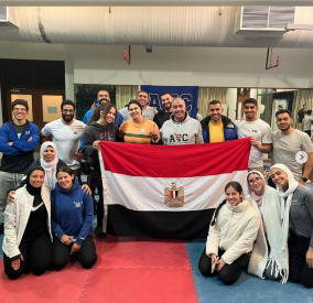 Males and females are standing and sitting around the Egyptian flag