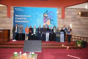 Males and females standing together and smiling. They are holding certificates. Text: Research and Creativity Convention 