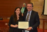 A man is handing a woman a certificate, They are smiling.