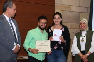 A male and a female are smiling and holding certificates