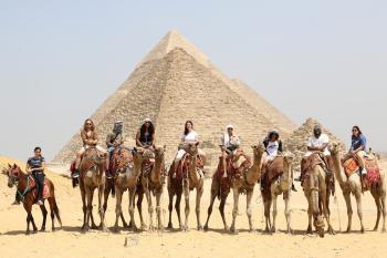 International students riding camels in front of the Pyramids