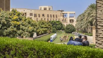 students sitting on a beanbag in the garden overlooking greenery and buildings 