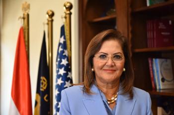 a woman with short brown hair wearing eye glasses and a light blue blazer