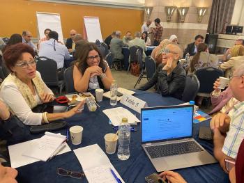 Greer Murphy sits with AUC faculty at a round table during a breakout session