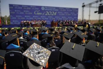 Graduates in black caps and gowns sit facing the stage at AUC&rsquo;s Class of 2024 commencement ceremony.