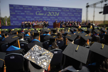 Graduates in black caps and gowns sit facing the stage at AUC&rsquo;s Class of 2024 commencement ceremony.