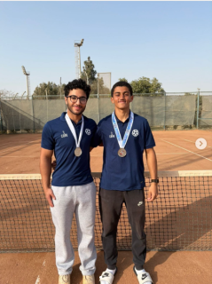 Male athletes standing and smiling. They are wearing medals