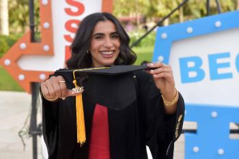 A female is wearing her cap and gown and smiling