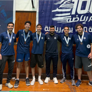 Male athletes are standing and smiling. They are wearing medals
