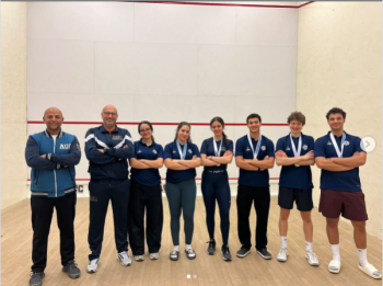 Male and female athletes standing and smiling. They are wearing medals
