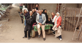 A class sits on the back of a horse drawn cart