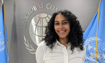 Zein Ibrahim stands next to the flag of the United Nations